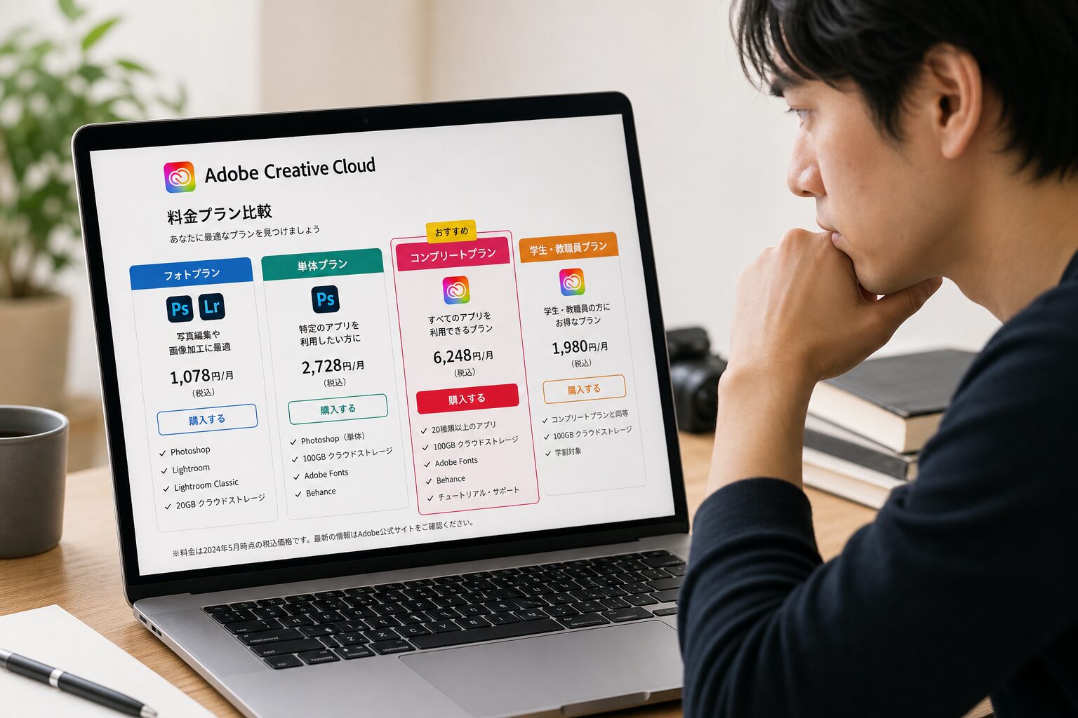 ノートパソコンの画面に映るAdobe Creative Cloudの料金プラン比較表を真剣に見比べているフリーランス男性